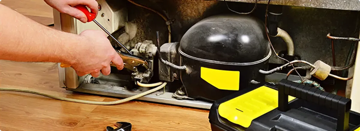 Refrigerator repair technician fixing the compressor and wiring in Marion, IA