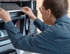 Appliance repair technician replacing a microwave vent filter in Cedar Rapids, IA