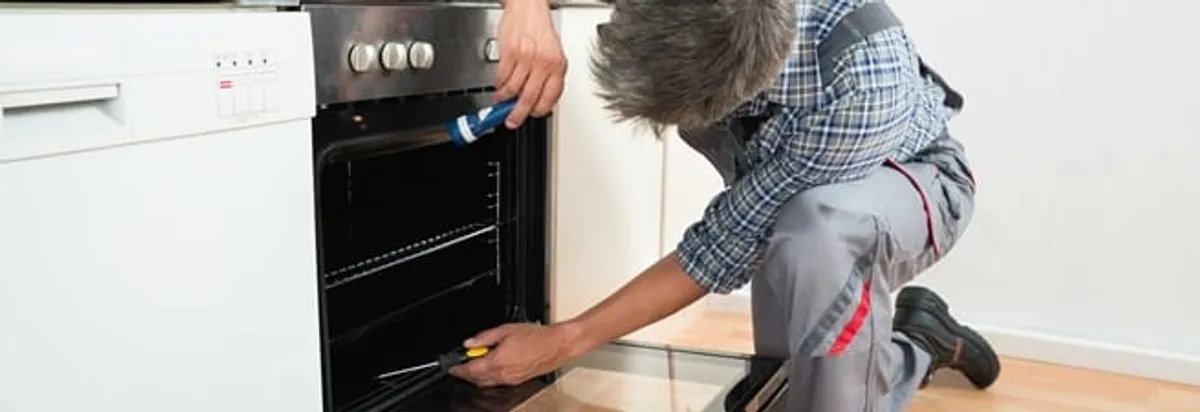 Oven repair technician inspecting and servicing an electric oven in Cedar Rapids, IA