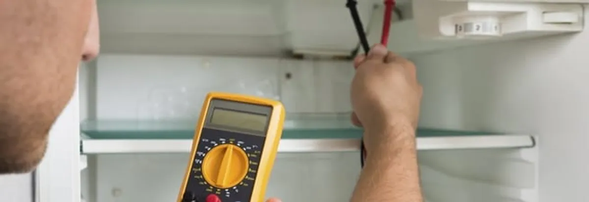 Refrigerator repair technician testing electrical components with a multimeter in Cedar Rapids, IA